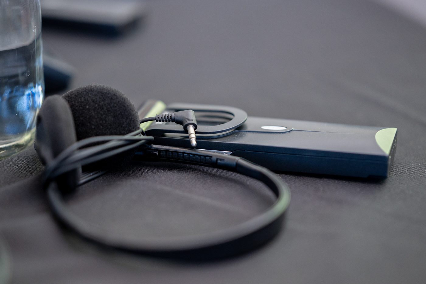 Close-up of a delegate belt-clip receiver with earpiece, used for simultaneous interpretation channels